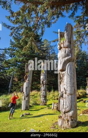 Fotografo con totem presso il sito patrimonio dell'umanità dell'UNESCO a SGang Gwaay, Haida Gwaii, British Columbia, Canada, Nord America Foto Stock