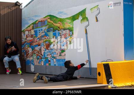 BUSAN, 7 marzo 2023 (Xinhua) -- Un bambino si pone per una foto con un dipinto a parete al Villaggio di Cultura di Gamcheon a Busan, Corea del Sud, 7 marzo 2023. Situato ai piedi di una montagna costiera a Busan, il villaggio culturale di Gamcheon è famoso per le case costruite in stile scala e i vicoli decorati con pitture murali e sculture. (Xinhua/Wang Yiliang) Foto Stock