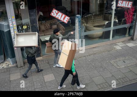 Tre uomini portano ciascuno un pezzo di arredamento, cassetti per una casa da qualche parte, lungo la Walworth Road a Camberwell, Londra sud, il 7th marzo 2023, a Londra, Inghilterra. Foto Stock