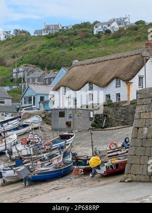 Barche da pesca sullo scalo di accesso al porto di Sennen Cove, con cottage con tetto in paglia sullo sfondo, Cornovaglia, Regno Unito Foto Stock