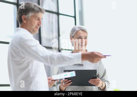 uomo d'affari che mostra qualcosa alla donna d'affari matura visto thru Foto Stock