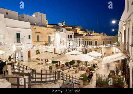 Ristoranti illuminati di sera in Piazza della libertà, Ostuni, provincia di Brindisi, Puglia, Italia, Europa Foto Stock