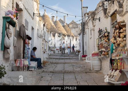 Case di trulli imbiancate e negozi di souvenir lungo la strada del centro storico, Alberobello, patrimonio dell'umanità dell'UNESCO, Puglia, Italia, Europa Foto Stock