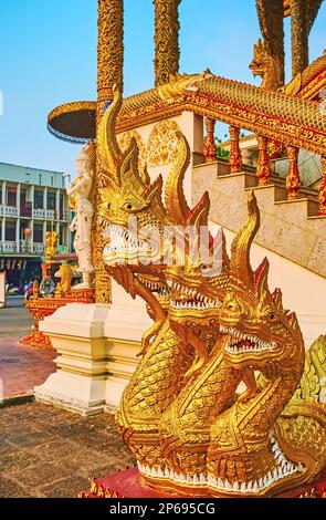 Le statue di serpenti dorati di Naga con grandi mascelle e denti bianchi di fronte alla biblioteca-santuario di Wat Buppharam, Chiang mai, Thailandia Foto Stock