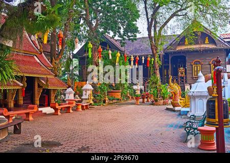 Le lanterne Lanna colorate nel giardino verde di Wat Ket Karam contro l'edificio monastico in legno d'epoca, Chiang mai, Thailandia Foto Stock