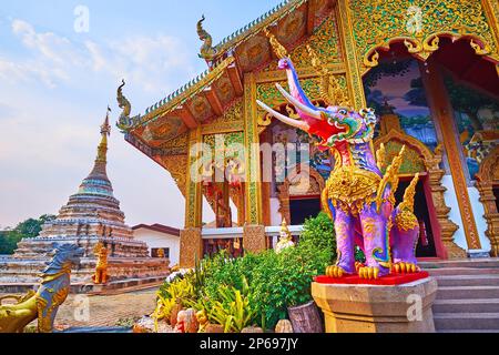 Il Chedi scolpito, Viharn ornato e colorato Hatsadiling (elefante alato) statua in primo piano, Wat Chetawan, Chiang mai, Thailandia Foto Stock