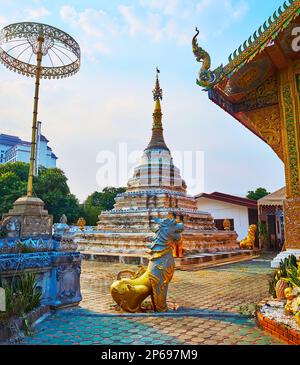 L'ombrello cerimoniale Chatra e la statua del leone di stile birmano Chinthè di fronte al vecchio Chedi di Wat Chetawan, Chiang mai, Thailandia Foto Stock