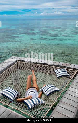 Giovane donna rilassante, atollo Meradhoo, Maldive Foto Stock