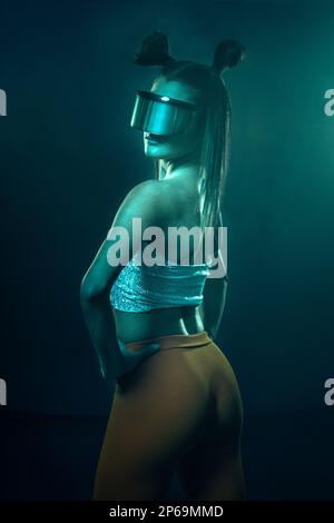 Ritratto di una bella donna cyber model che indossa occhiali futuristici sulla testa con luce al neon in un ambiente tecnologico virtuale Foto Stock