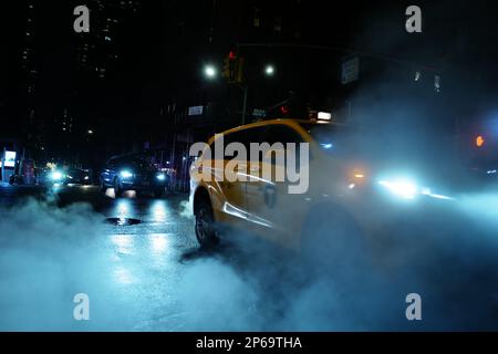 Taxi che guida attraverso il vapore in una notte piovosa a New York City Foto Stock