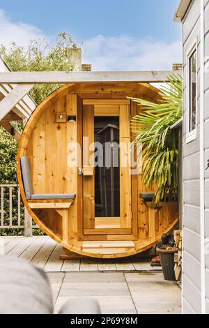 un'area esterna con vasca idromassaggio e pentole a terra davanti ad una struttura in legno simile a una botte Foto Stock