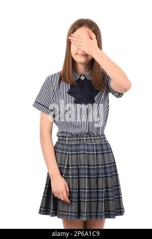 Giovane bella ragazza in uniforme scolastica su sfondo bianco, sorridente e ridente con mano sul viso che copre gli occhi per sorpresa. Concetto cieco. Foto Stock