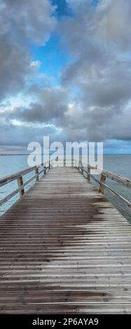 Vuoto molo di legno per il Ria de Aveiro in Portogallo, con cielo drammatico e acqua calma. Torreira, Murtosa - Portogallo. Foto Stock