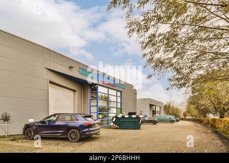 un'auto blu parcheggiata di fronte ad un edificio con una awd sul lato e un uomo in piedi accanto ad esso Foto Stock