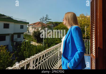 Donna in tuta si erge sul balcone di una casa privata. Foto Stock
