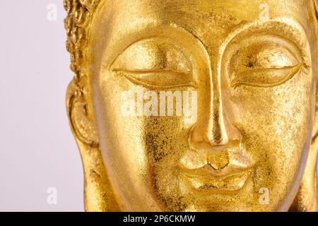 Faccia della statua del Buddha d'oro isolata su sfondo bianco Foto Stock