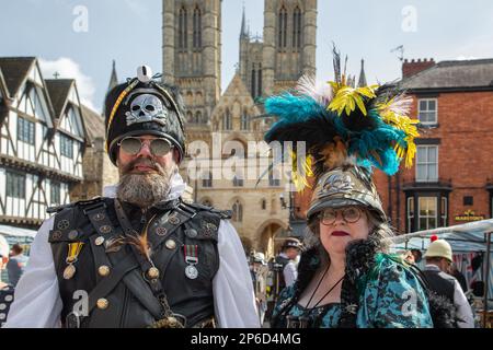 Ritratto di una coppia steampunk di mezza età con la Cattedrale di Lincoln sullo sfondo. Foto Stock