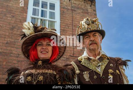 Ritratto di una coppia steampunk di mezza età in piedi di fronte a una casa. Foto Stock