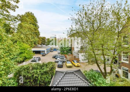 Amsterdam, Paesi Bassi - 10 Aprile, 2021: Un appartamento a londra, con auto parcheggiate sul vialetto e alberi che costeggiano la strada dall'ultimo piano al terreno Foto Stock