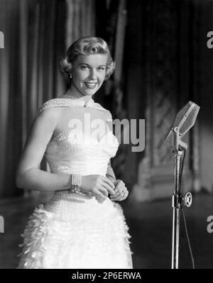 1953 ca : l'attrice e cantante DORIS DAY ( vero nome Doris Mary Ann Kappelhoff , nato il 3 aprile 1924 Cincinnati, Ohio, USA ) In un film di pubblicity still - FILM - FILM - attrice cimatografica - blonde - bionda - scollatura - decollete' - neckopening - microfono - microfono - bracciale - bracciale - perle - perle - gioielli - gioielleria - gioielleria - gioielleria - gioielli - bijoux - sorriso - sorriso - sorriso ---- Archivio GBB Foto Stock