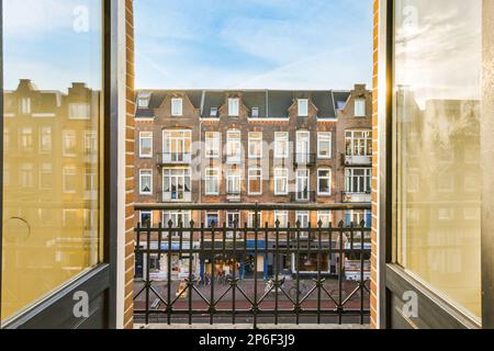 Amsterdam, Paesi Bassi - 10 aprile 2021: Un'area esterna con edifici sullo sfondo e persone che camminano sulla strada attraverso la finestra sull'altro lato Foto Stock