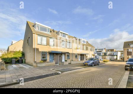 una strada con auto parcheggiate sul lato e case sul retro, tutte rivolte l'una verso l'altra Foto Stock