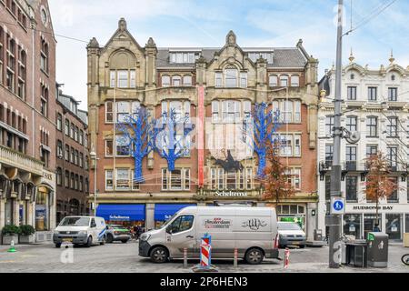 Amsterdam, Paesi Bassi - 10 aprile 2021: Un edificio nel mezzo di un'area urbana con auto parcheggiate sulla strada e persone che camminano lungo la strada Foto Stock