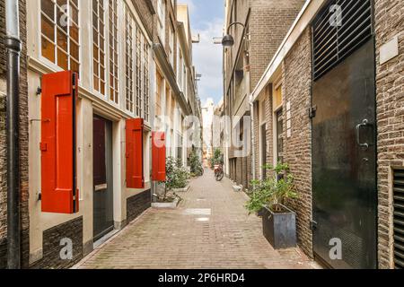 un vicolo con porte rosse ed edifici in mattoni su entrambi i lati, sullo sfondo è un cielo blu pieno di nuvole bianche Foto Stock