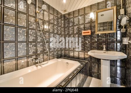 un bagno con piastrelle bianche e nere alle pareti e una vasca indipendente nell'angolo Foto Stock