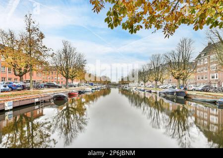 alcune barche in acqua e gli edifici su entrambi i lati, con gli alberi che si riflettono in acqua come si riflettono Foto Stock