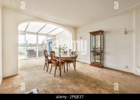 una sala da pranzo con un arco nella parete e una vista sul giardino dalla porta del soggiorno Foto Stock