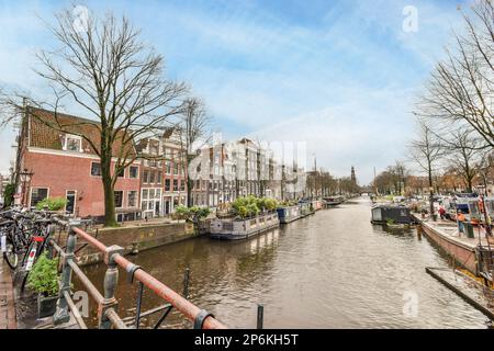 Amsterdam, Paesi Bassi - 10 aprile 2021: Un canale con barche e case sullo sfondo, preso da un ponte in un tour in barca intorno ai canali di amsterdam Foto Stock