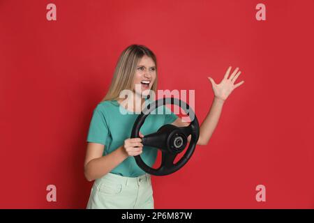 Giovane donna emozionale con volante su sfondo rosso Foto Stock