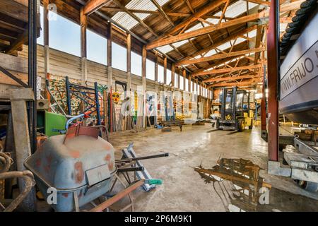 l'interno di un edificio che viene utilizzato come officina per vari tipi di metallo e altre cose in esso Foto Stock