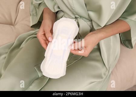 Giovane donna con imbottitura mestruale sul divano, primo piano Foto Stock