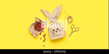 Sacchetto regalo per coniglietto di Pasqua, caramelle e forbici su sfondo giallo Foto Stock