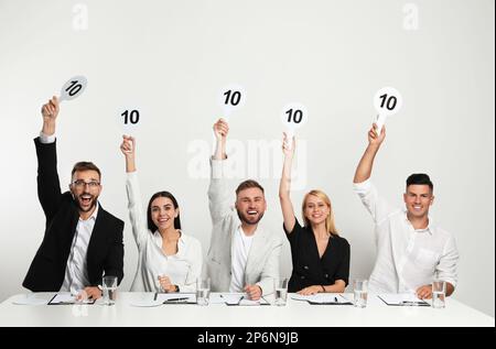 Gruppo di giudici con i segni con il punteggio più alto a tavola su sfondo bianco Foto Stock