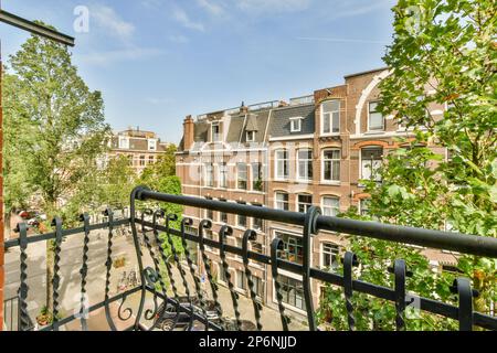 Amsterdam, Paesi Bassi - 10 aprile 2021: Un balcone con biciclette parcheggiate sulle ringhiere e sugli edifici sullo sfondo, come si vede dalla finestra di un appartamento Foto Stock