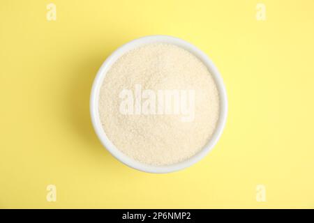 Polvere di gelatina in ciotola su sfondo giallo, vista dall'alto Foto Stock