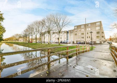 Amsterdam, Paesi Bassi - 10 aprile, 2021: Una strada allagata con automobili parcheggiate sul lato e gli edifici sul retro, gli alberi si riflettono nell'acqua Foto Stock