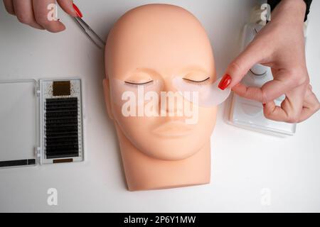 Testa da training manichino con false ciglia e kit ciglia per pratica di estensione. Concetto di estensione del ciglia di addestramento. Foto Stock