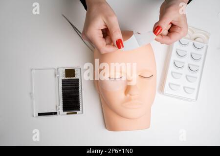 Formazione di base per costruire ciglia su un manichino in silicone. Lavorare con il nastro sotto gli occhi prima dell'estensione delle ciglia, vista dall'alto. Foto Stock