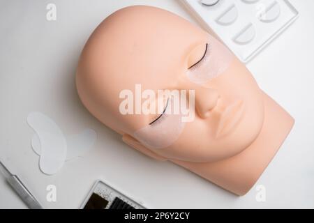 Testa da training manichino con false ciglia e kit ciglia per pratica di estensione. Concetto di estensione del ciglia di addestramento Foto Stock