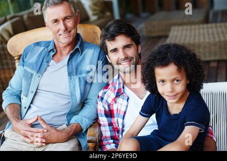 Tempo di padre e figlio. Tre generazioni di maschi di una famiglia seduti insieme a casa. Foto Stock
