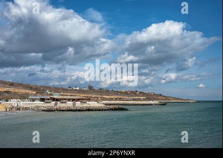 Odessa, Ucraina 18.02.2023. Nuvole bianche nel cielo blu sul mare vicino alla spiaggia suburbana di Odessa, Ucraina, in una giornata invernale soleggiata Foto Stock