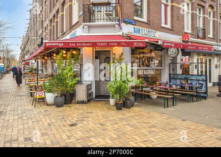 un piccolo ristorante sul lato di una strada in mattoni davanti ad un edificio con tende rosse Foto Stock