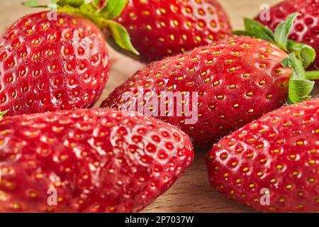 Fragole fresche selezionate, impilate su fondo in legno Foto Stock