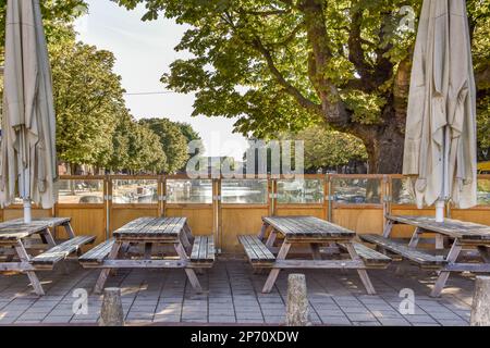 Amsterdam, Paesi Bassi - 10 aprile, 2021: Un'area all'aperto con tavoli e ombrelloni all'ombra, in una giornata di sole in un grande albero può essere visto nel Foto Stock