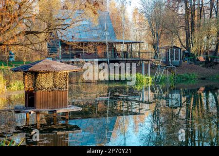 Casa estiva sulla riva di uno stagno. Capanna dei pescatori sopra lo stagno Foto Stock