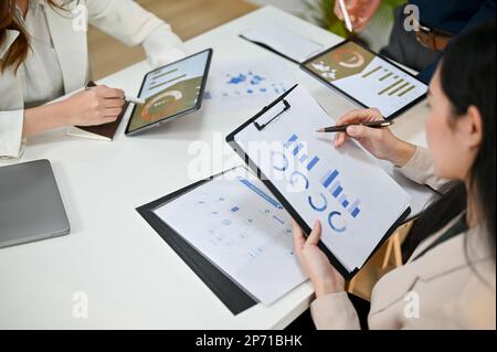 Immagine ravvicinata di una donna d'affari asiatica o di una analista finanziaria femminile professionista che rivede i dati finanziari su report con il suo team durante il Meet Foto Stock